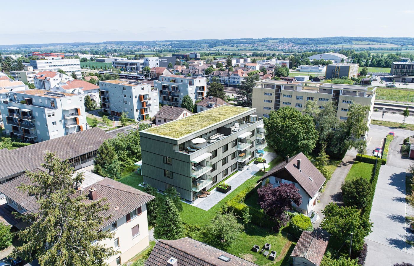 Drohnenansicht eines Wohngebäudes mit begrüntem Dach in einem Quartier