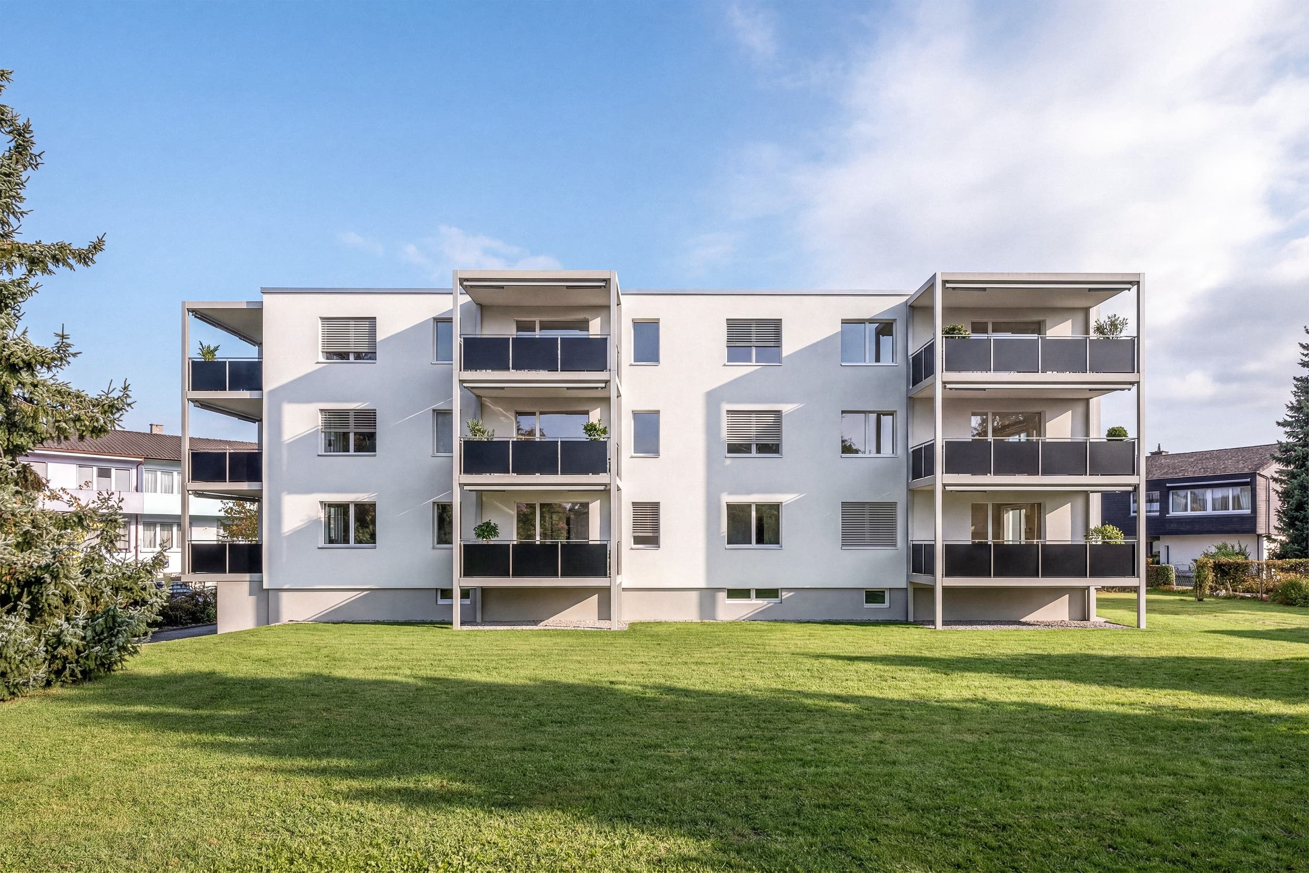 Aussenvisualisierung der MFH Sanierung Biberist mit heller Fassade, Balkonen und Garten